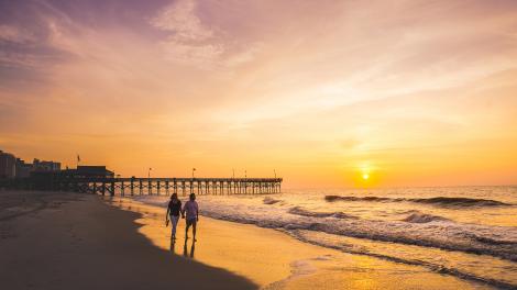 在美特尔海滩码头享受落日时光的一对爱人