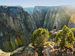Randonneur admirant les profondeurs et les parois striées du Black Canyon of the Gunnison National Park, dans le Colorado
