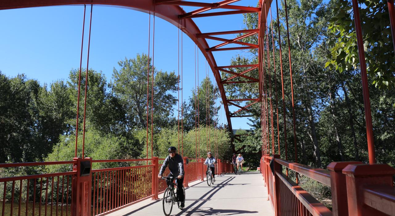 Cyclists bike along the Boise River Greenbelt on a sunny afternoon.