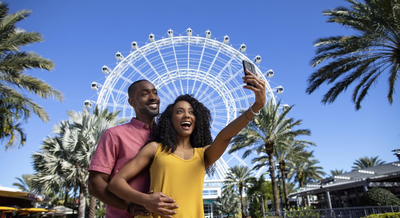 Couple posing in front of the Wheel at ICON Park in Orlando, Florida